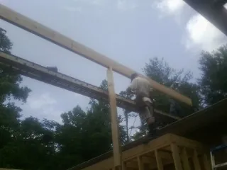 Carpenter setting a ridge beam over a new addition frame — Ice Dam Removal by Roofing Brothers in Nekoma