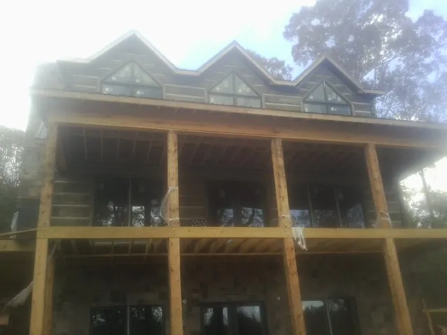 Dormers and porch framing on a large log home under construction — Roof Coating work by our crew in Nekoma