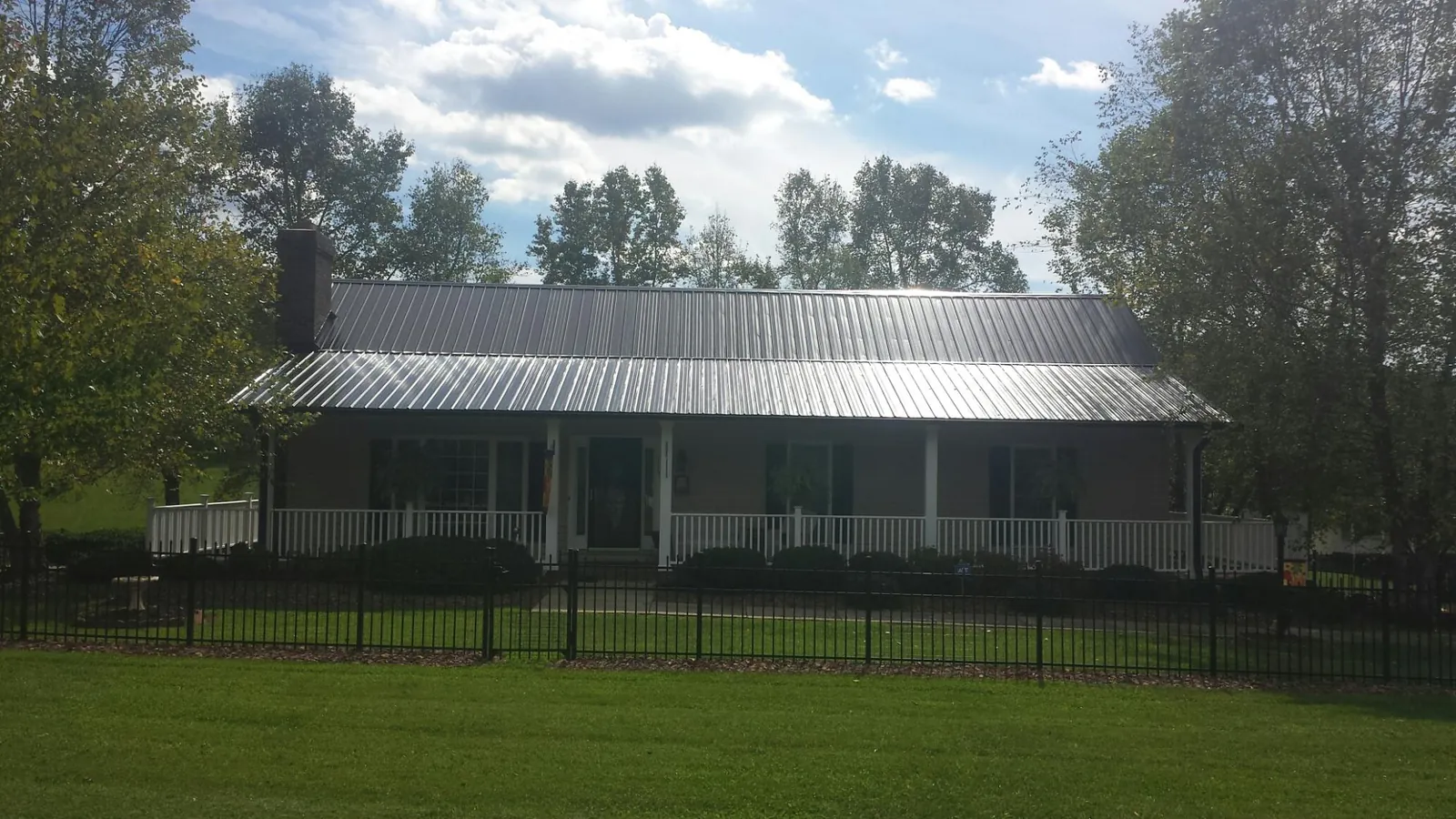 Gray metal roof on a brick ranch with a full width front porch — Gutter Guard Installation work by our crew in Nekoma