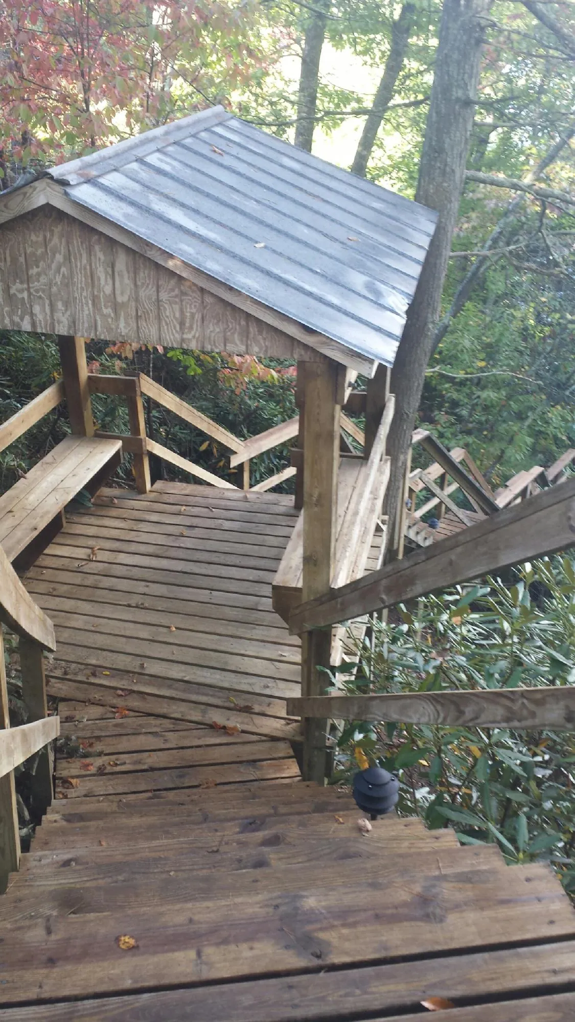 Metal roofed shelter over wooden steps on a wooded walkway — Skylight Repair & Installation work by our crew in Nekoma