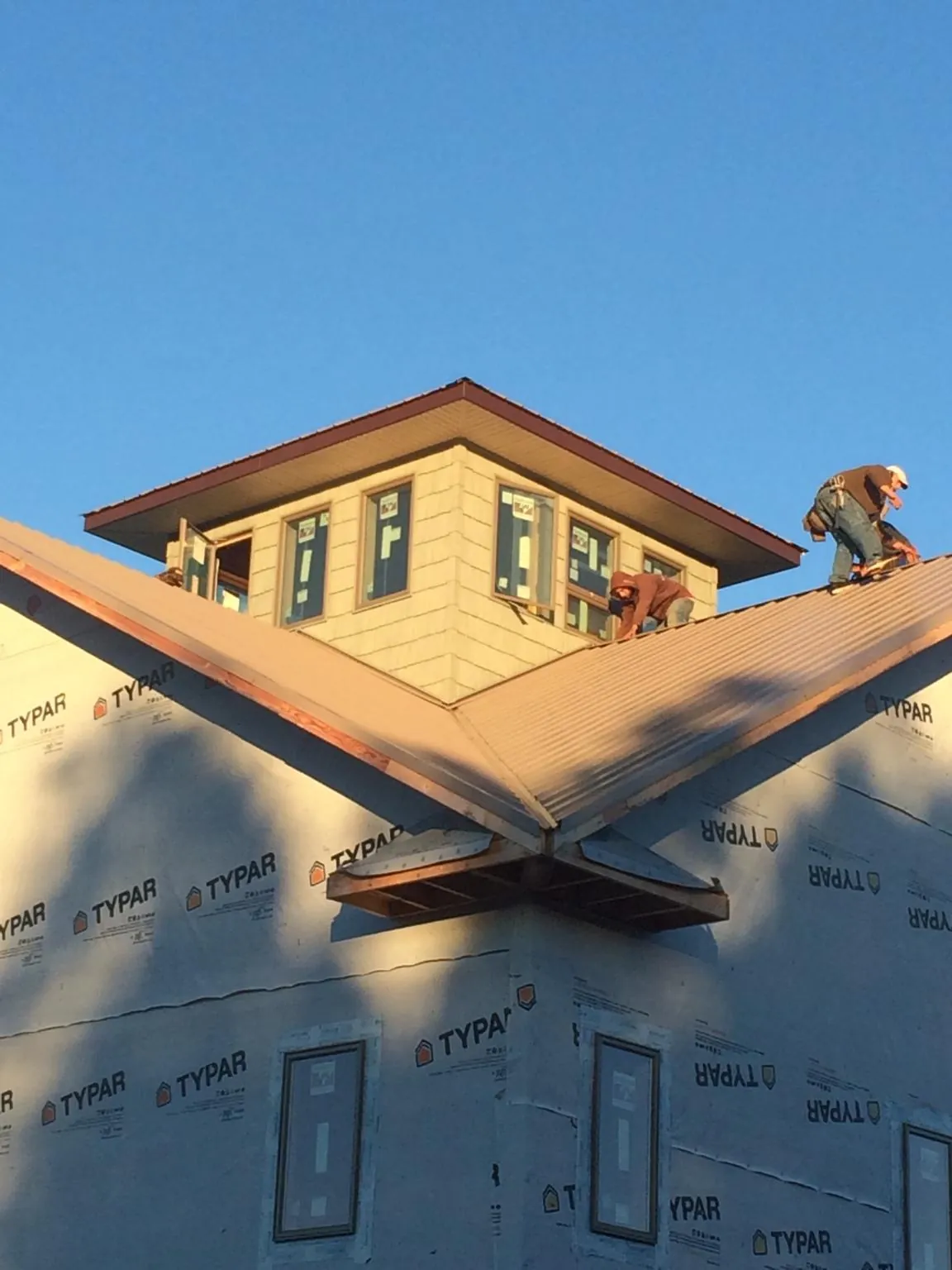 Roofers working around a rooftop cupola on a new metal roof at sunset — Roof Waterproofing in Nekoma by Roofing Brothers
